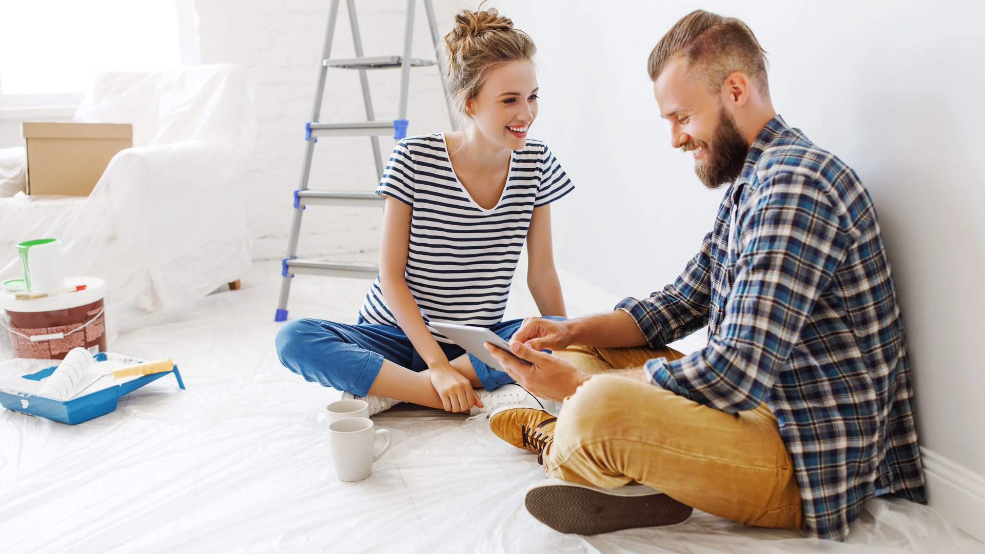 Zwei Personen sitzen auf dem Boden und schauen auf ein Tablet.