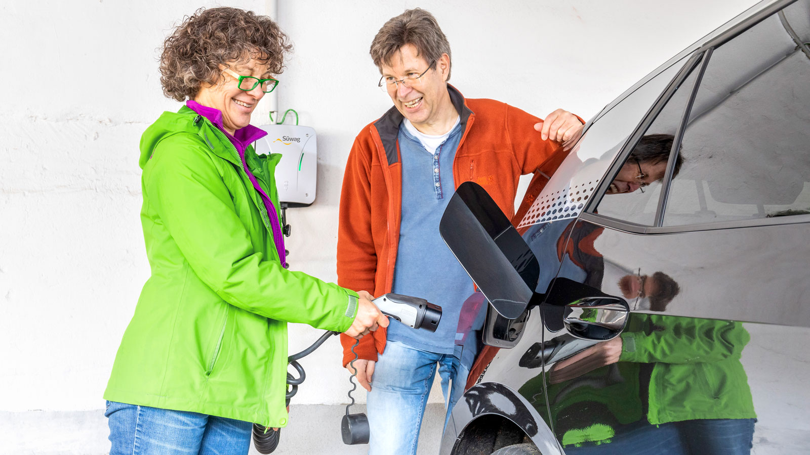 Frau lädt Elektroauto auf.