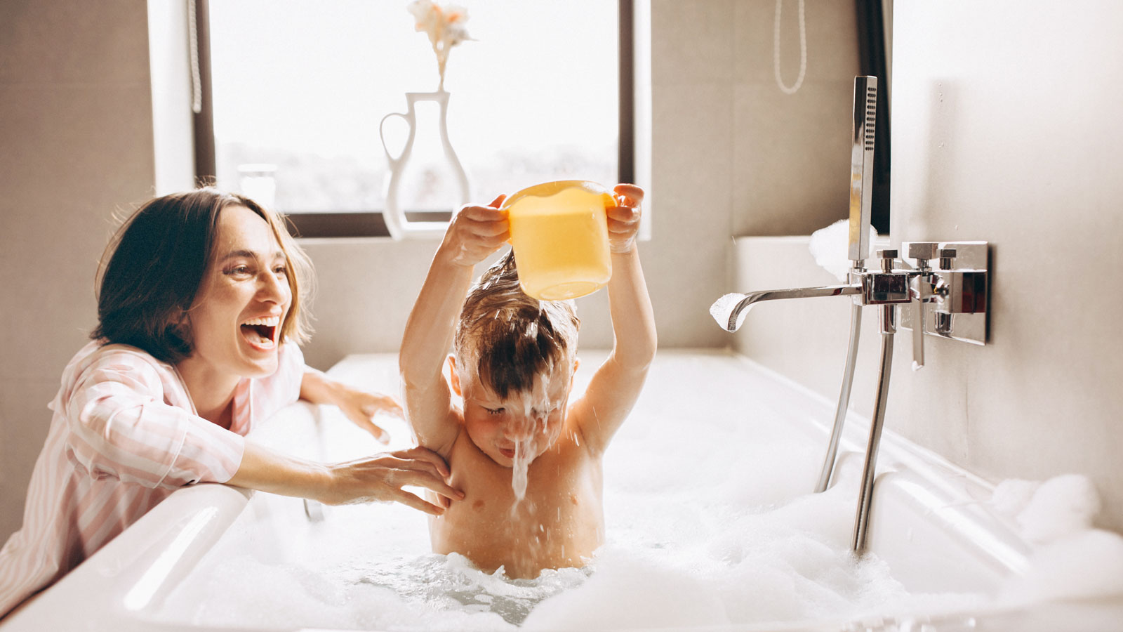 Kind wird von Erwachsener mit Wasser übergossen, Schaumbad.