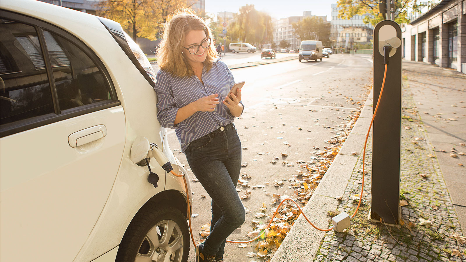 Frau lädt Elektroauto auf.