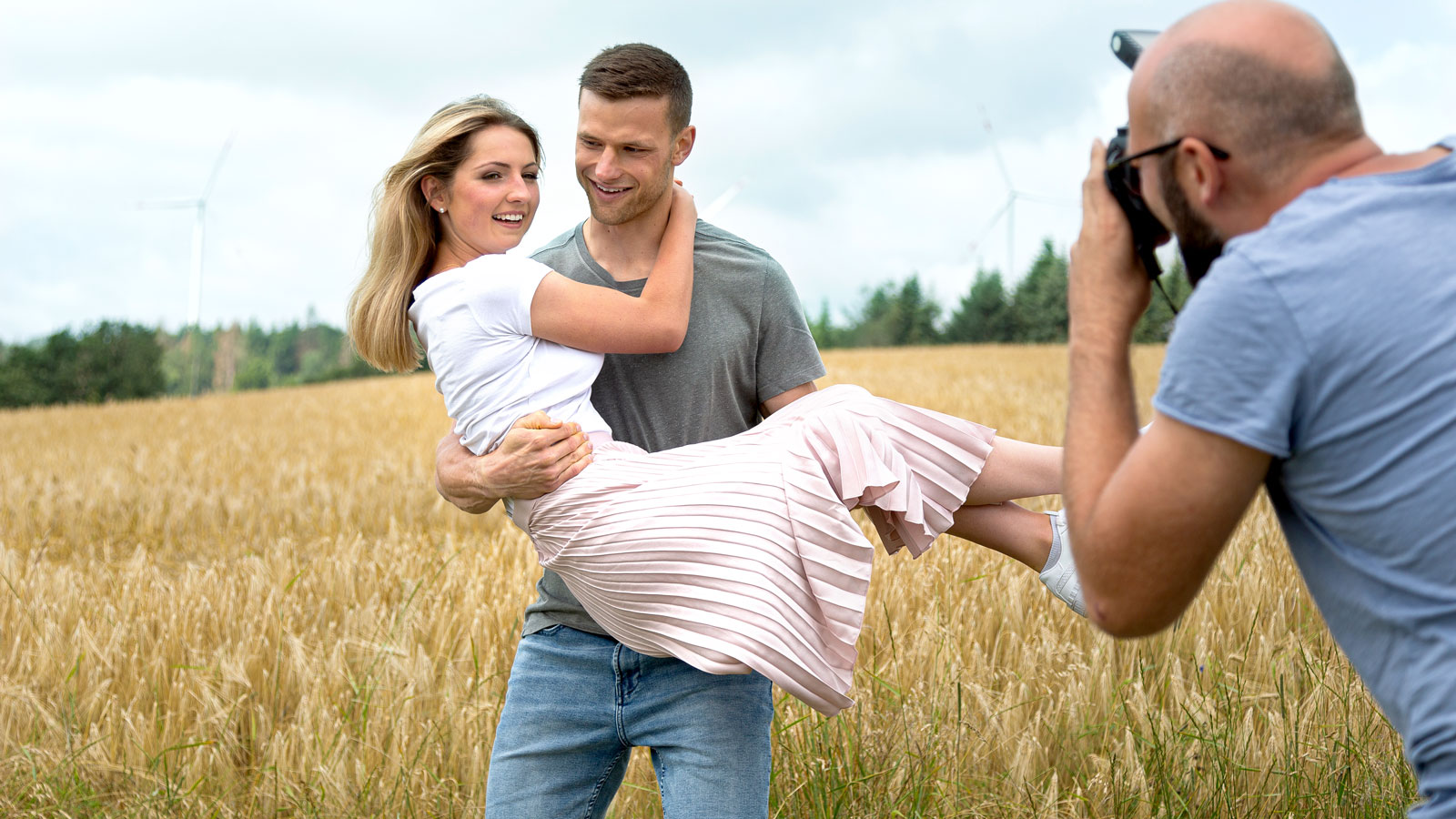 Mann trägt Frau auf einem Feld.