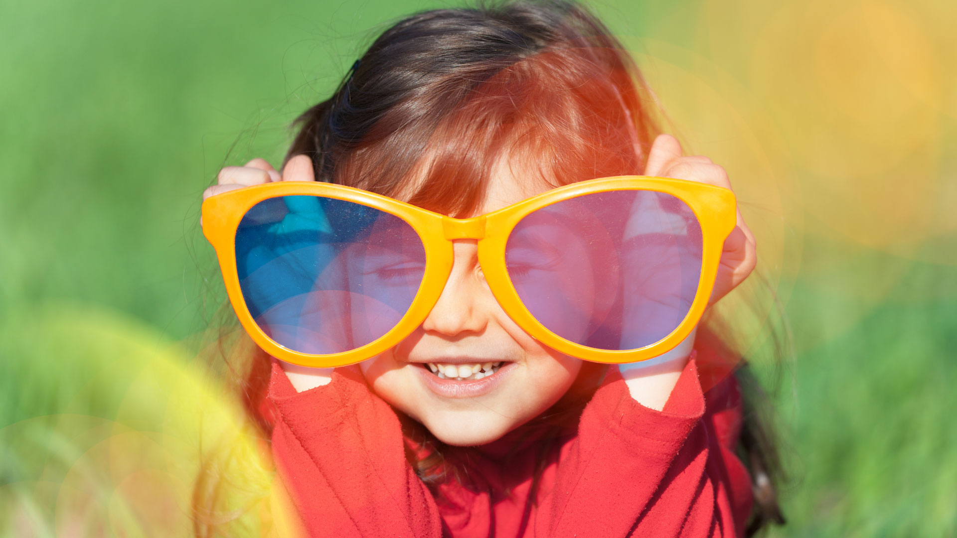 Kind mit übergroßen gelben Sonnenbrillen