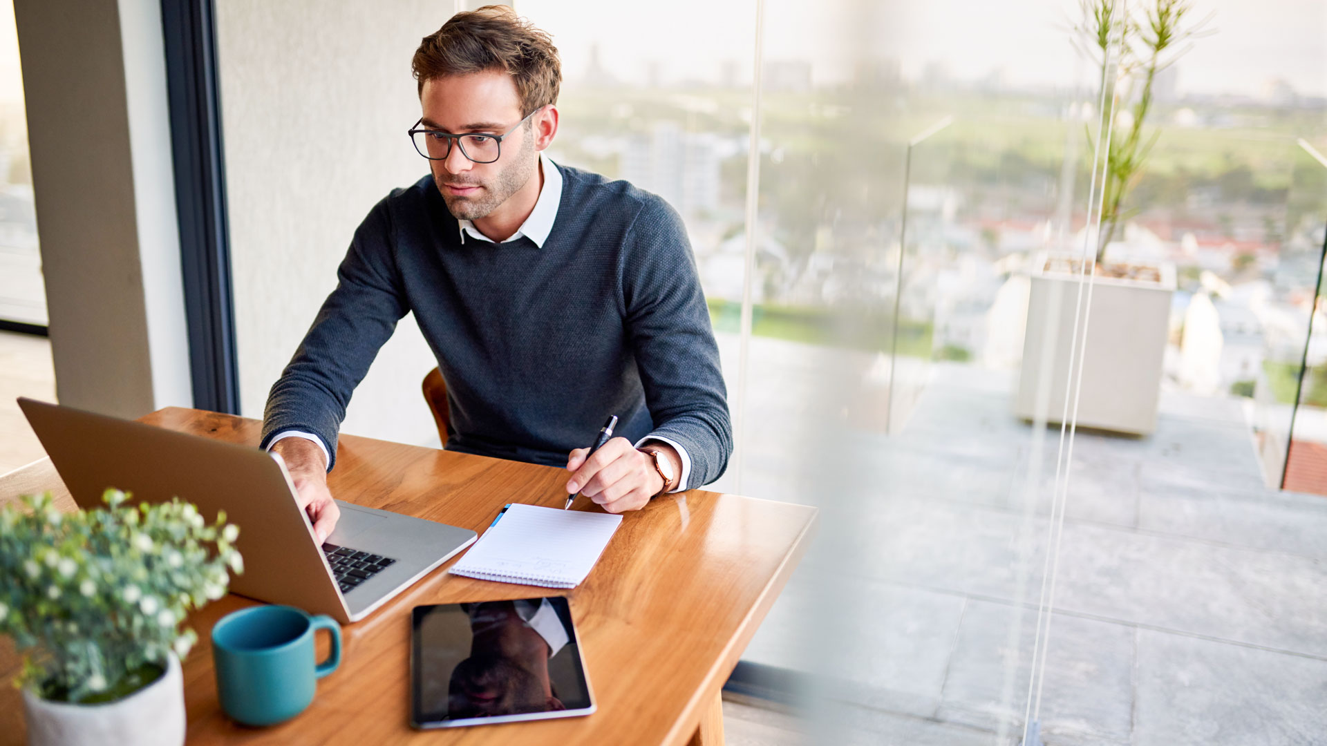 Mann mit Laptop und Notizbuch am Tisch