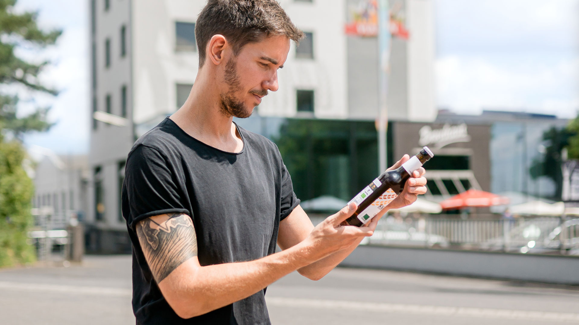 Mann liest Etikett einer Glasflasche.