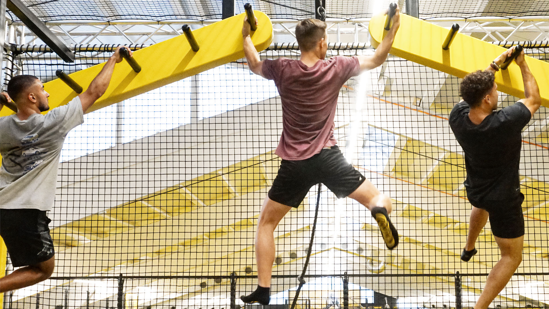 Drei Männer klettern an einer Ninja-Hindernisbahn.