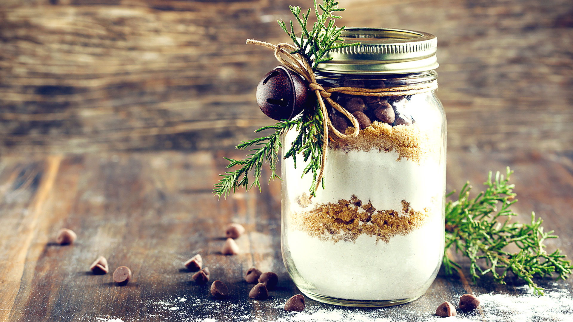 Glas mit Schichten aus Mehl, Zucker und Kakao, dekoriert mit Tannenzweig und Kordel