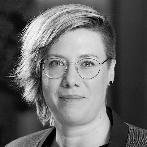 Frau mit kurzen, dunklen Haaren und runden Brillengläsern