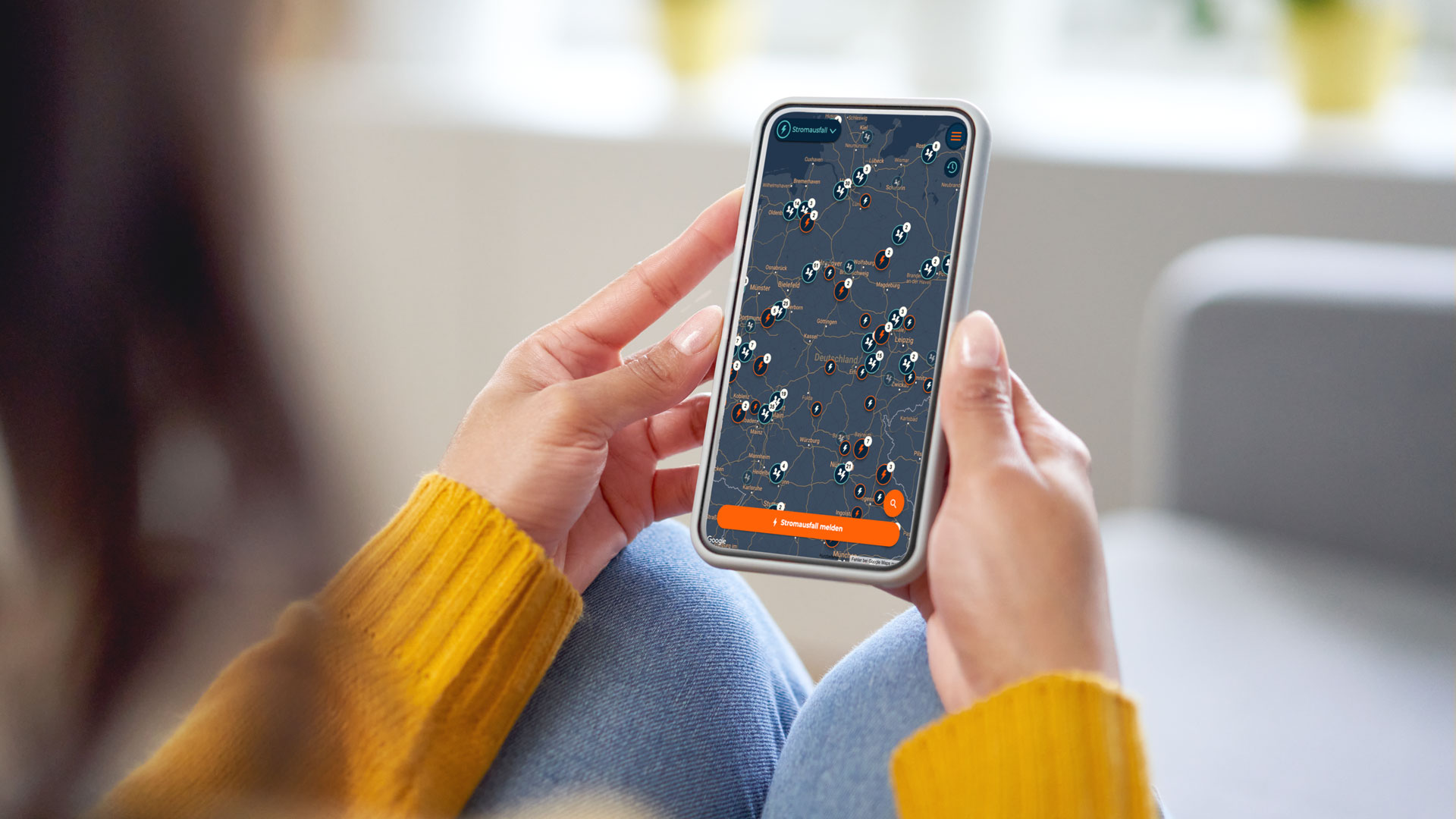 Person hält Smartphone mit Karte, die Stromausfälle anzeigt.