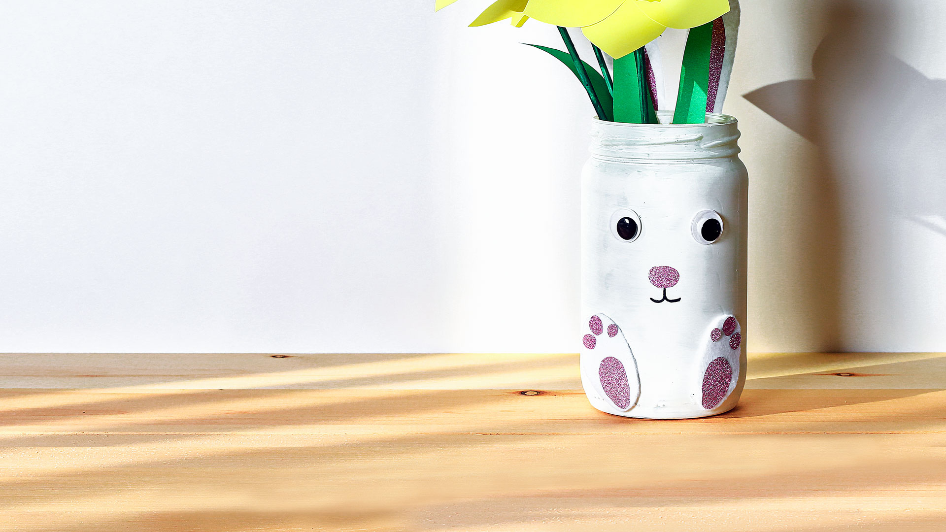 Bemalter Glasbehälter mit gelben Papierblumen