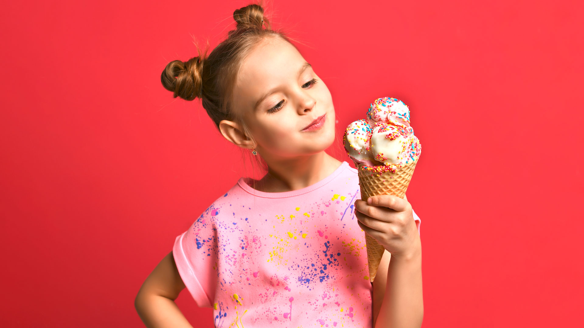 Jüngiges Mädchen hält Waffeleis mit Streuseln.