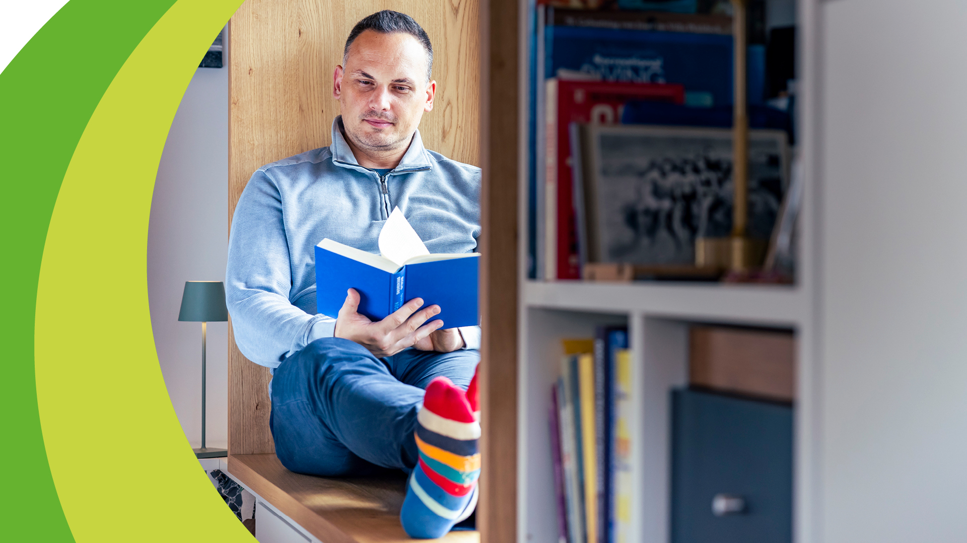 Mann liest Buch auf Fensterbank