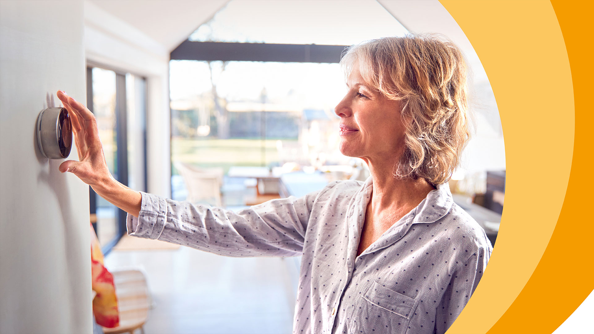 Frau verstellt Thermostat an Wand.