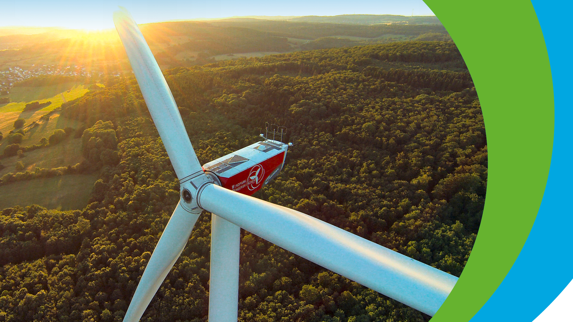 Windkraftanlage mit Rotorblättern vor blauem Himmel und Landschaft