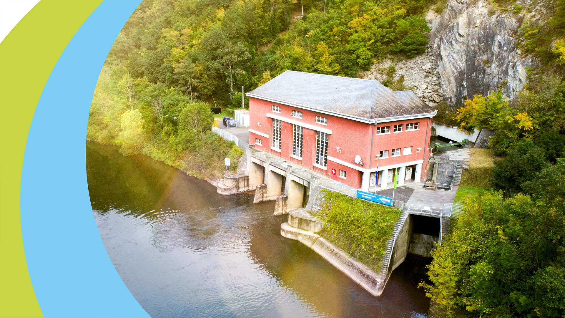 Rotes Gebäude mit Satteldach an Flussufer, Wasserkraftwerk