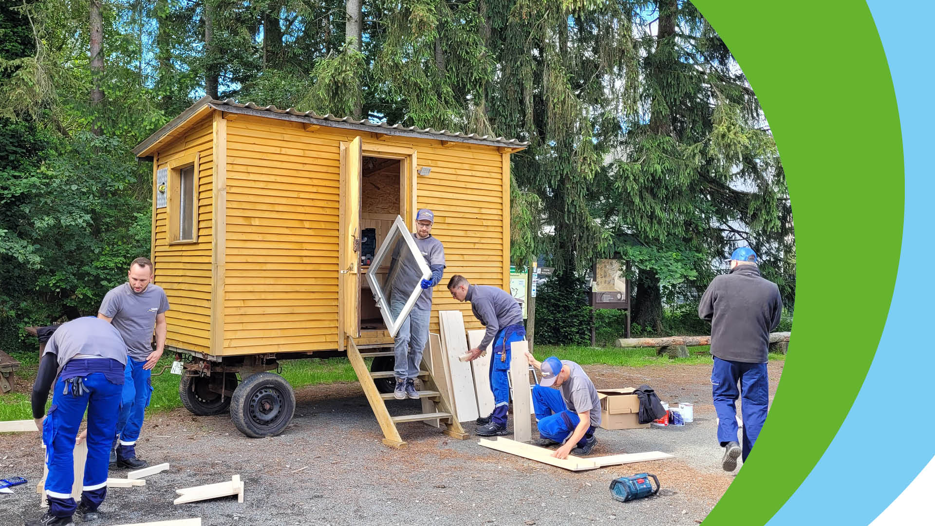 Bau einer mobilen Toilettenanlage durch mehrere Personen in Arbeitskleidung.