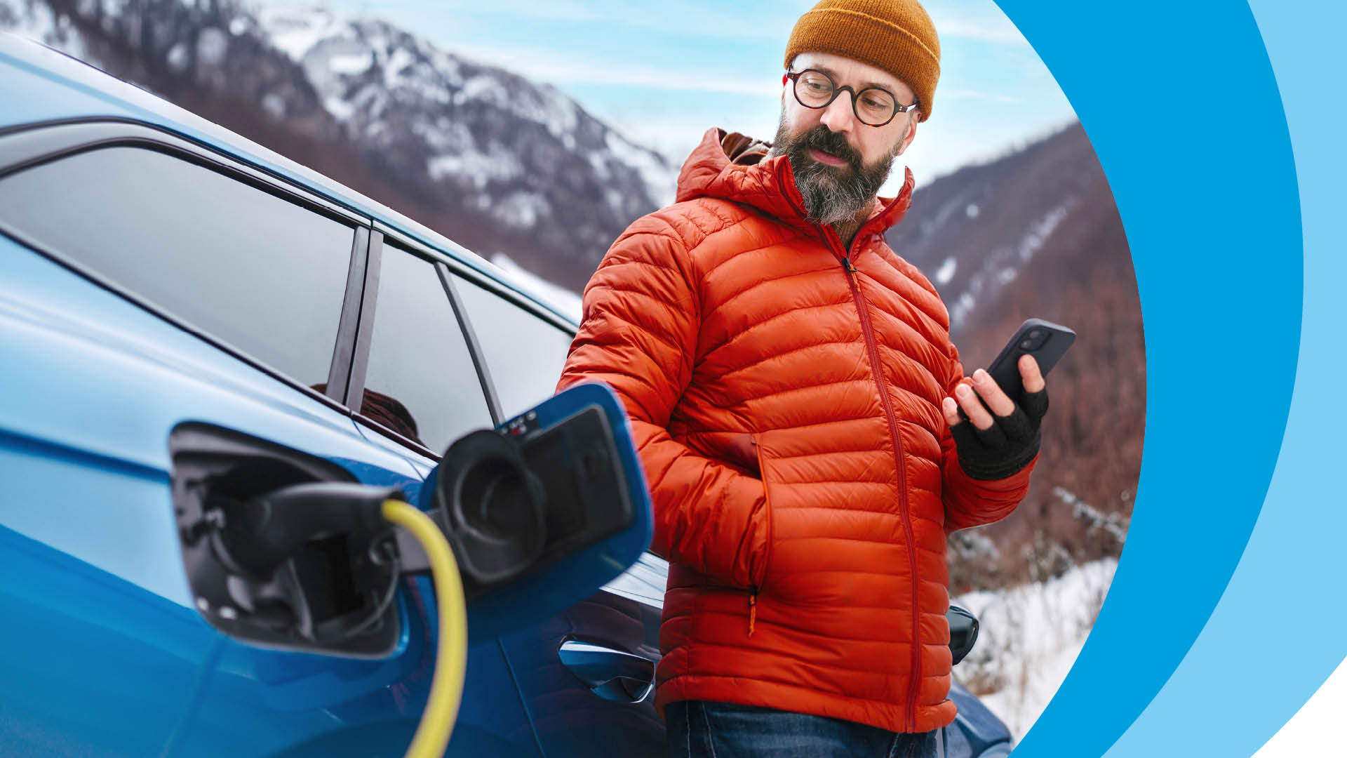 Mann lädt Elektroauto auf, hält Smartphone in der Hand.